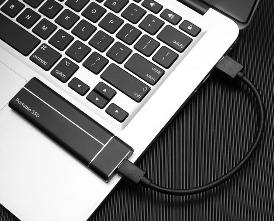 Slim Metal Frosted Design Portable SSD in black color that is attached to a laptop